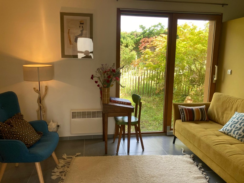 Vue d’ensemble du cabinet : fauteuil, canapé, bureau et vue sur le jardin